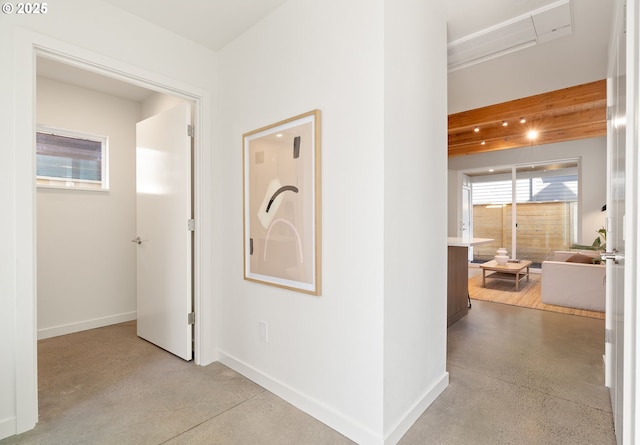 hall with concrete floors and baseboards