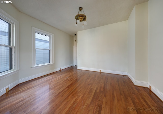 spare room featuring an inviting chandelier and hardwood / wood-style flooring