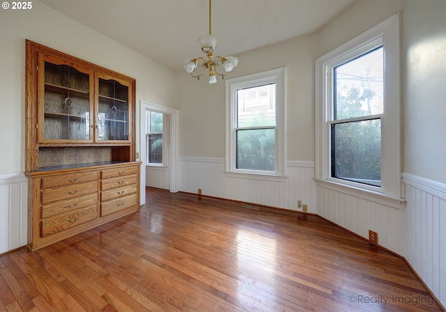 unfurnished dining area with dark hardwood / wood-style flooring and a chandelier