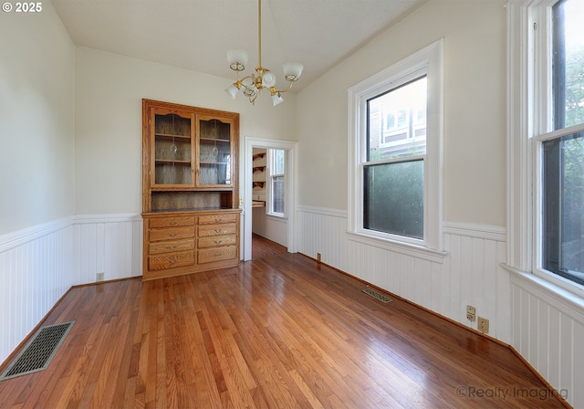 unfurnished dining area with hardwood / wood-style floors and an inviting chandelier