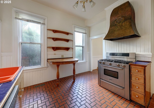 kitchen featuring dishwasher, ceiling fan, premium range hood, wood walls, and high end stainless steel range oven