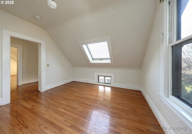 bonus room featuring light wood-type flooring and vaulted ceiling with skylight