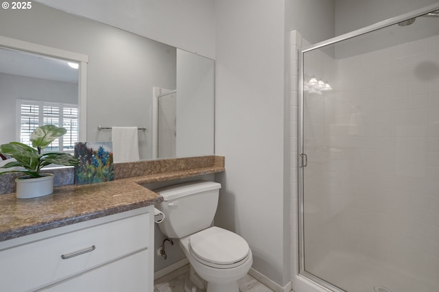 bathroom featuring a shower with door, vanity, and toilet