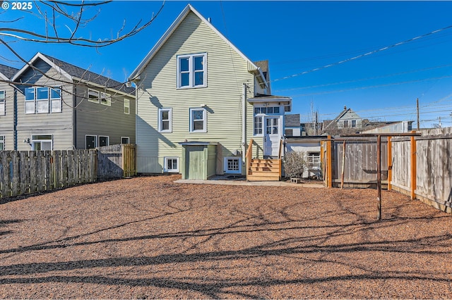 rear view of property with entry steps and a fenced backyard