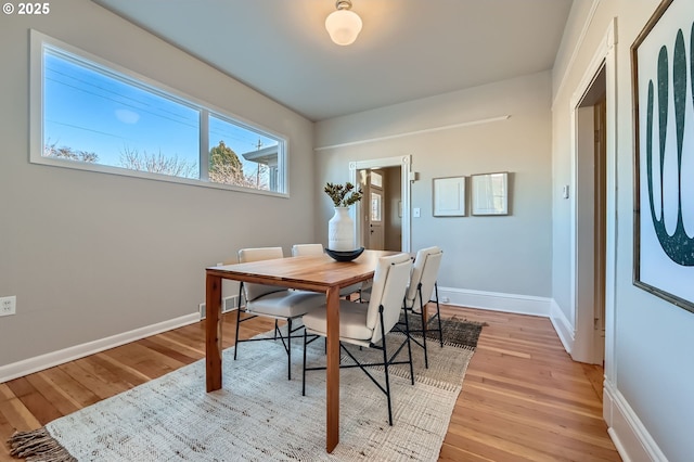 dining area with light wood-type flooring and baseboards