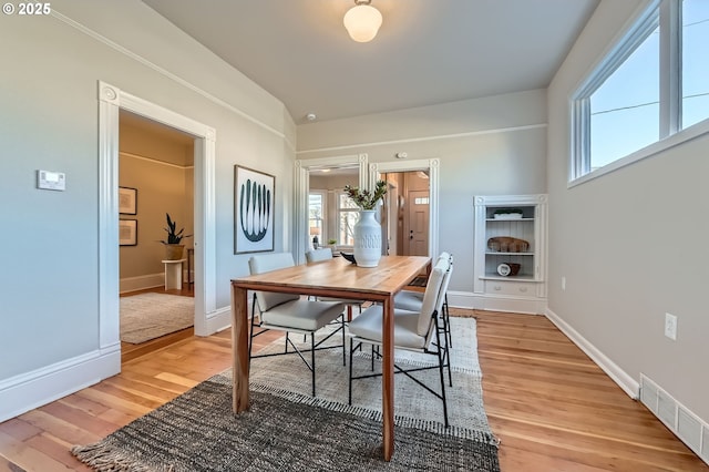 dining space featuring light wood-type flooring, visible vents, and baseboards