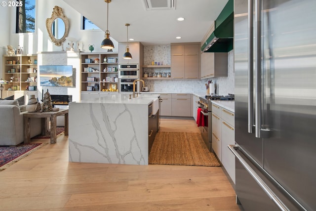 kitchen featuring open shelves, extractor fan, light wood-type flooring, premium appliances, and gray cabinetry