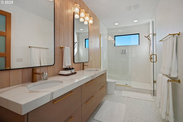 full bathroom featuring double vanity, a sink, speckled floor, and a shower stall