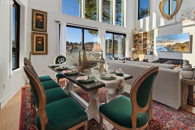 dining room featuring baseboards, wood finished floors, and a towering ceiling
