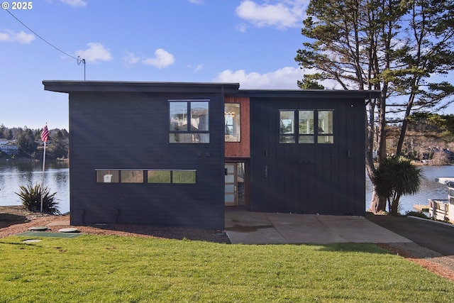 view of front of house featuring a patio, a water view, and a front lawn