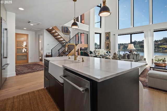 kitchen with appliances with stainless steel finishes, a sink, light wood-style floors, open floor plan, and visible vents