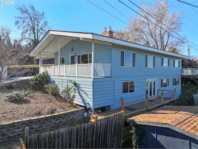 view of side of property with a deck, fence, and a chimney