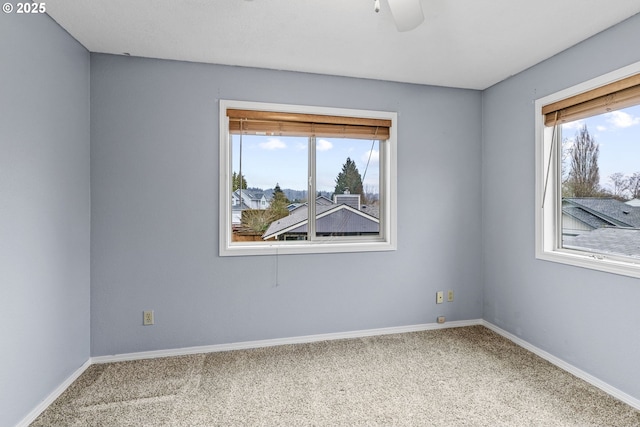 carpeted spare room featuring ceiling fan and plenty of natural light