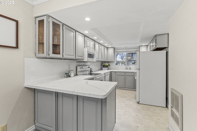 kitchen featuring gray cabinets, white appliances, and kitchen peninsula