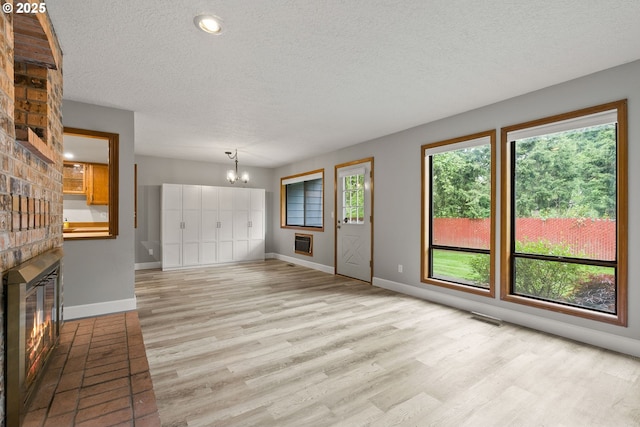 434 SW Eastman Pkwy, Gresham, OR 97080 - unfurnished living room featuring a textured ceiling, a brick fireplace, a chandelier, light wood-style floors, and baseboards