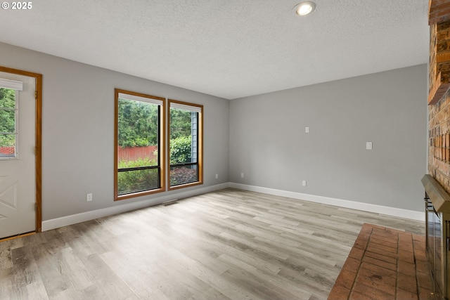 434 SW Eastman Pkwy, Gresham, OR 97080 - unfurnished living room featuring a large fireplace, healthy amount of natural light, a textured ceiling, and wood finished floors