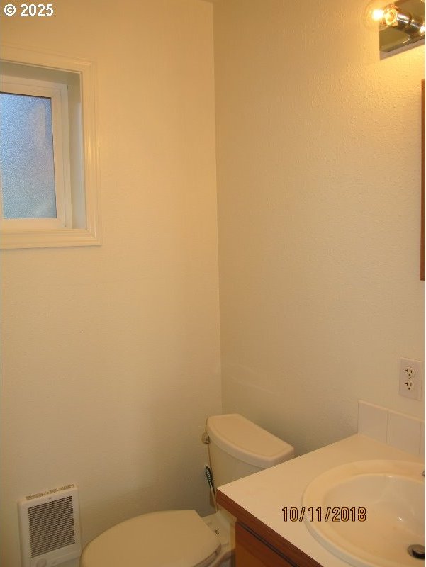 half bath featuring toilet, vanity, and heating unit