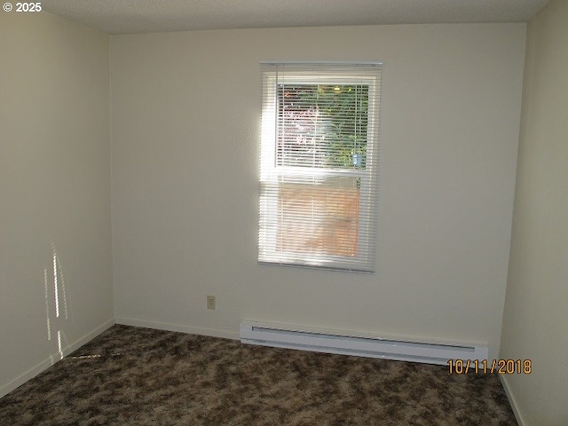 unfurnished room featuring a healthy amount of sunlight, a baseboard heating unit, and dark colored carpet