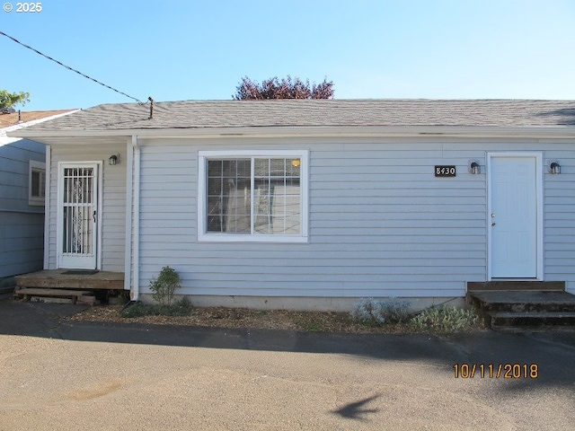 property entrance featuring a shingled roof