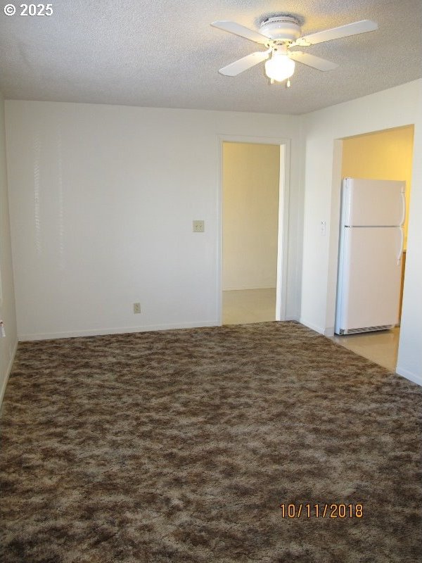 unfurnished room with a textured ceiling, a ceiling fan, and carpet floors