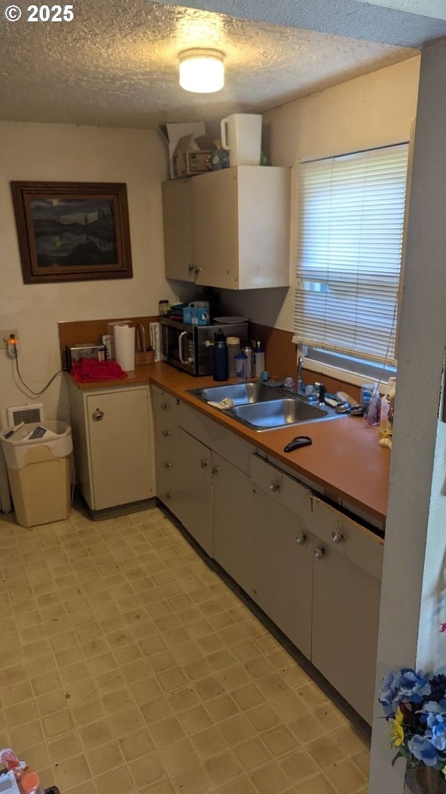 8428 SE 60th Ave, Portland, OR 97206 - kitchen with a sink, stainless steel microwave, white cabinetry, a textured ceiling, and light flooring