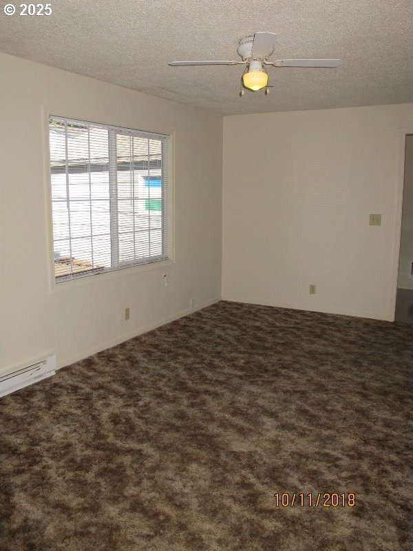 carpeted empty room with ceiling fan, a textured ceiling, and baseboard heating
