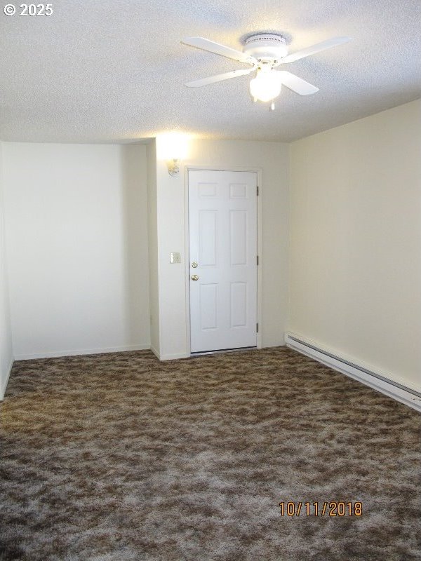 unfurnished room featuring baseboard heating, a textured ceiling, ceiling fan, and carpet floors