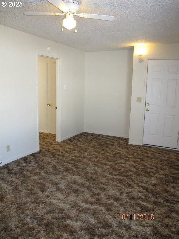 carpeted empty room with a textured ceiling and ceiling fan