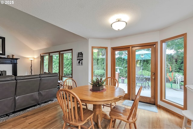 19642 SW 56th Ct, Tualatin, OR 97062 - dining space with light wood-type flooring, plenty of natural light, a textured ceiling, a brick fireplace, and vaulted ceiling