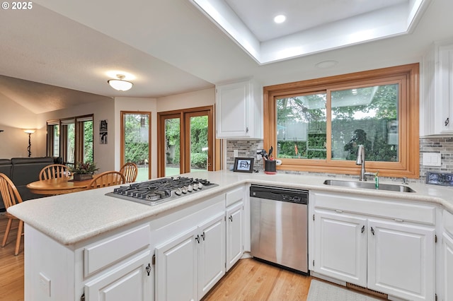 19642 SW 56th Ct, Tualatin, OR 97062 - kitchen with stainless steel appliances, a sink, a peninsula, backsplash, and light wood-style flooring
