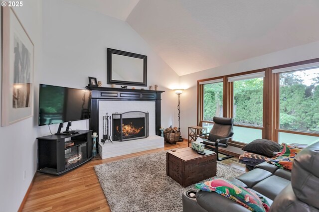 19642 SW 56th Ct, Tualatin, OR 97062 - living area with vaulted ceiling, a fireplace, light wood-style floors, and baseboards