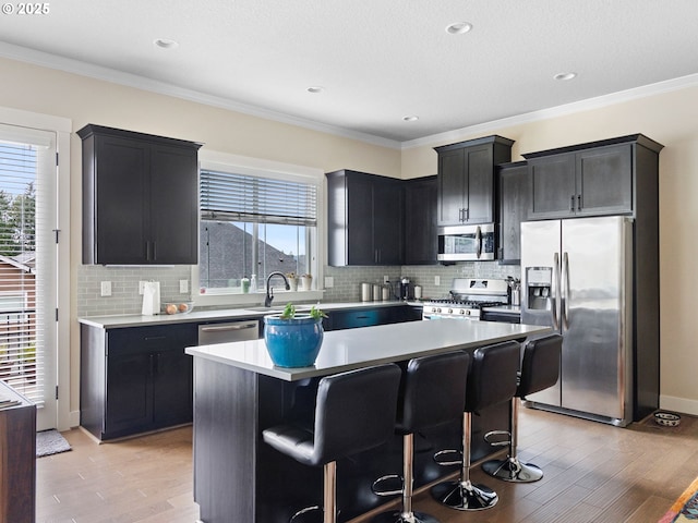 kitchen with stainless steel appliances, a center island, a breakfast bar area, and light hardwood / wood-style floors