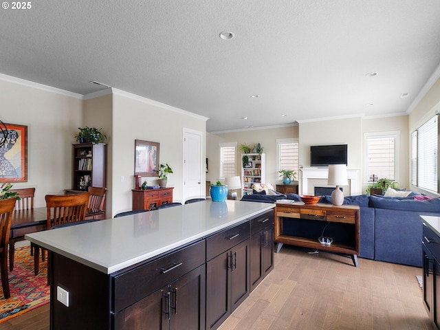 kitchen with crown molding, dark brown cabinets, light hardwood / wood-style floors, a textured ceiling, and a kitchen island