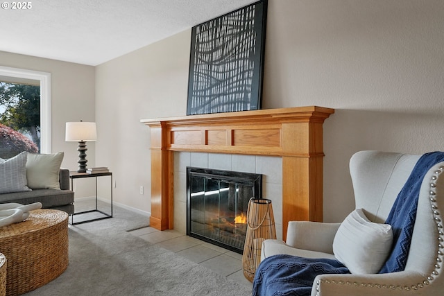 sitting room featuring baseboards, a tiled fireplace, and light colored carpet