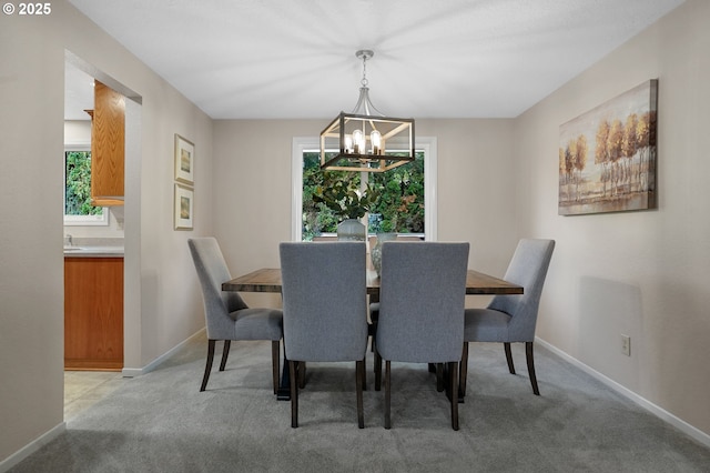 dining space with a chandelier, light colored carpet, and baseboards