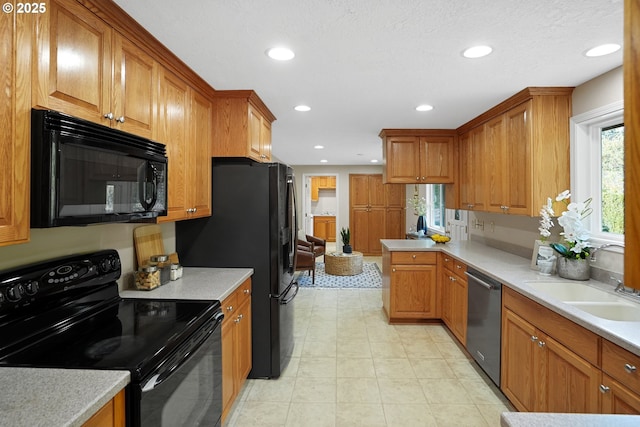 kitchen with black appliances, recessed lighting, a sink, and brown cabinets