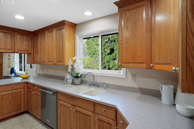 kitchen featuring dishwasher, brown cabinets, a sink, and light countertops