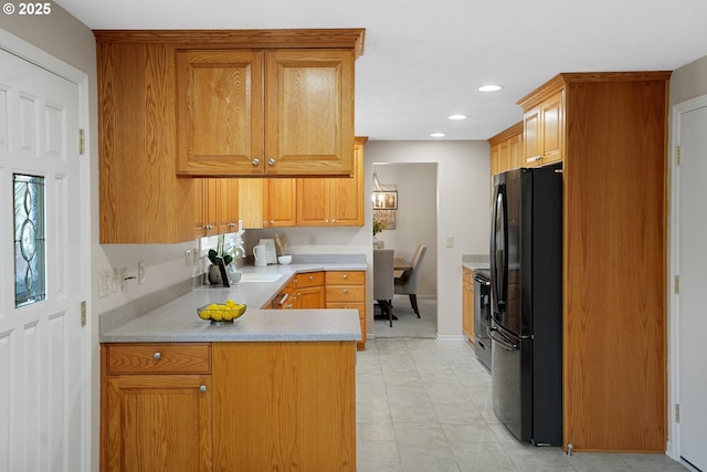 kitchen featuring freestanding refrigerator, a peninsula, light countertops, a wealth of natural light, and recessed lighting