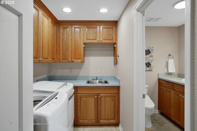 washroom featuring light tile patterned floors, a sink, visible vents, independent washer and dryer, and cabinet space