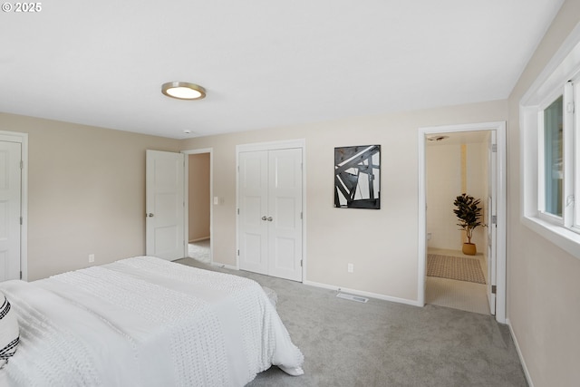 carpeted bedroom with visible vents, baseboards, and a closet