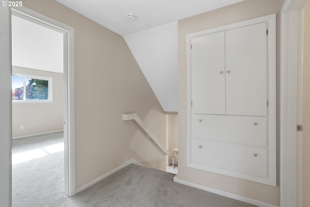 interior space featuring lofted ceiling, baseboards, carpet flooring, and an upstairs landing