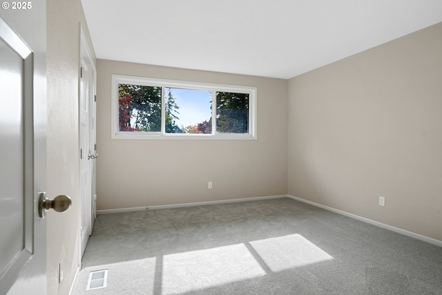 carpeted spare room with visible vents and baseboards