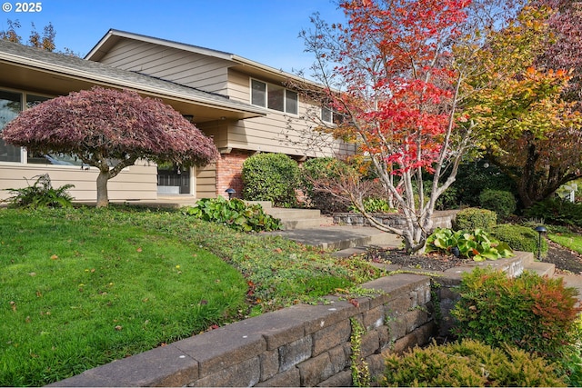 exterior space featuring brick siding and a front yard