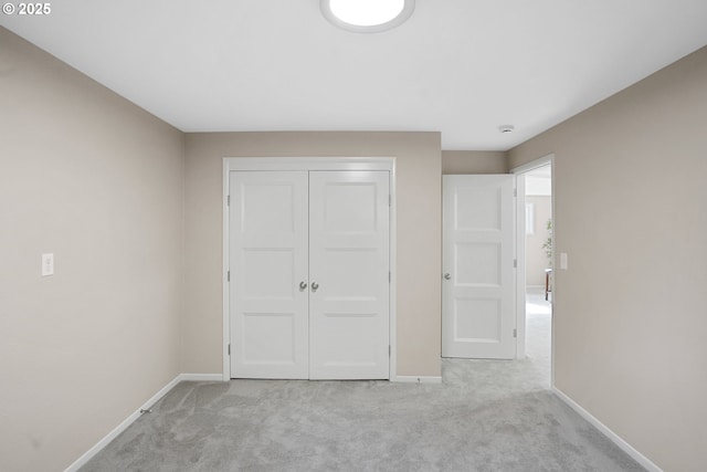 unfurnished bedroom featuring light carpet, baseboards, and a closet