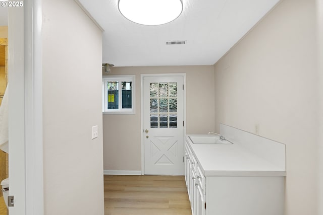 doorway to outside featuring light wood-type flooring, visible vents, and a sink