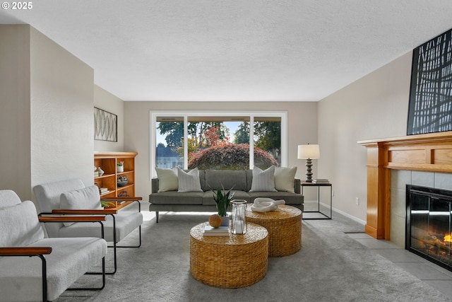 living room featuring carpet floors, a textured ceiling, baseboards, and a tiled fireplace