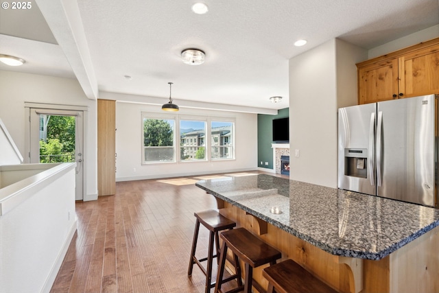 201 Selkirk Ln, Hood River, OR 97031 - kitchen featuring stainless steel fridge with ice dispenser, open floor plan, light wood-type flooring, a tiled fireplace, and a kitchen bar
