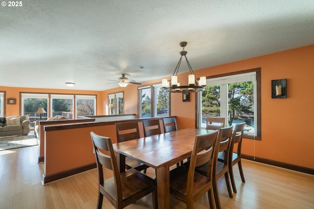 dining space with light hardwood / wood-style flooring, a chandelier, and a textured ceiling