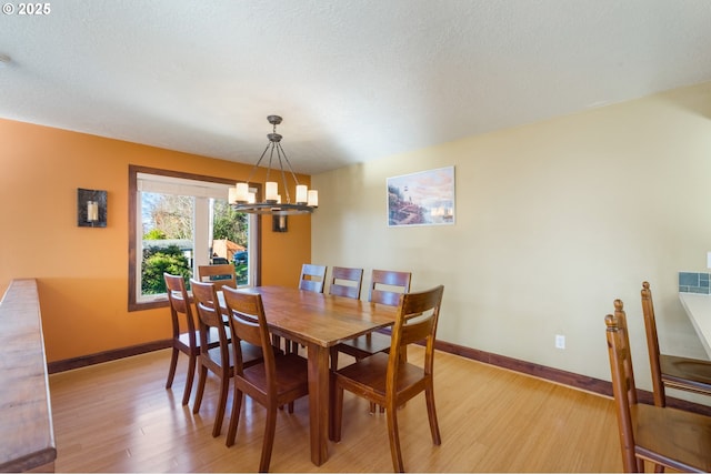 dining area featuring an inviting chandelier, a textured ceiling, and light wood-type flooring