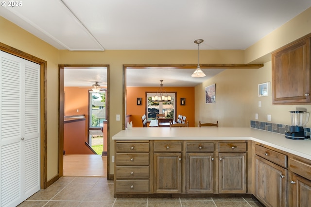 kitchen with pendant lighting, tile patterned floors, kitchen peninsula, and an inviting chandelier